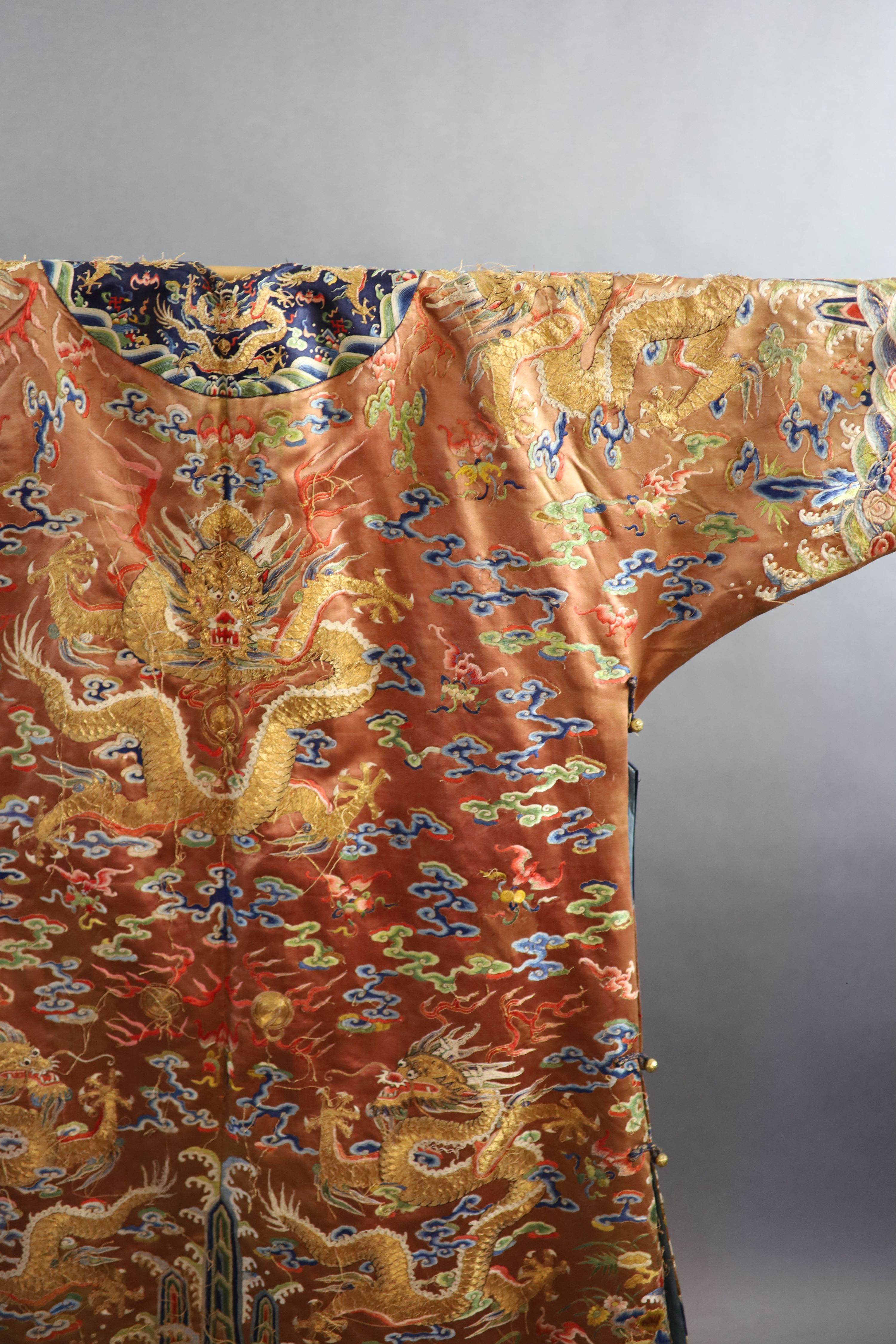 A Chinese apricot embroidered silk ‘dragon’ formal court robe, jifu, late Qing Dynasty, 131cm long, some alterations